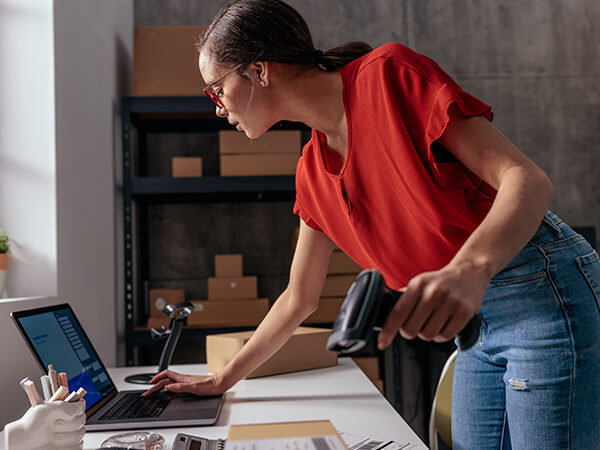 Woman looking at laptop and holding tag scanner