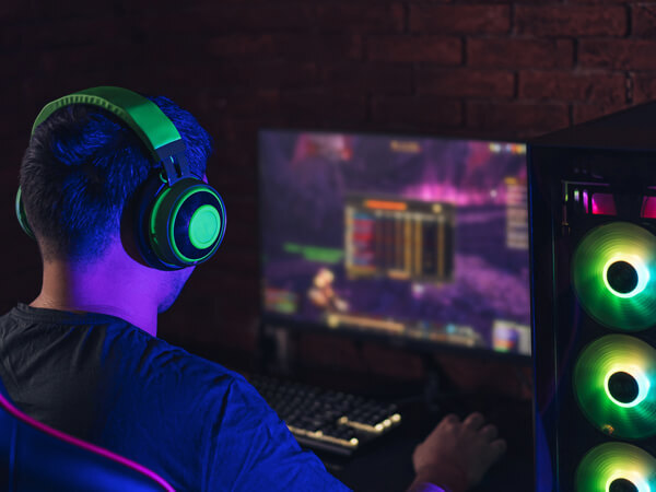 Man with headphones sitting in dark with computer lit up
