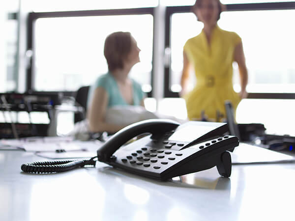 Business Vo IP Features 600x450 Two women in office with phone on desk in focus