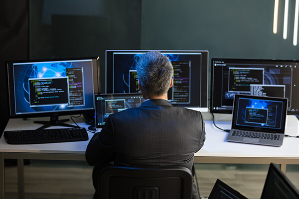 Man sitting at a desk monitoring many computers