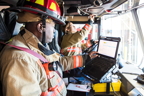 Two people in a fire truck looking at a computer screen