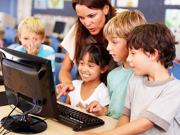 Teacher working with kids looking at a computer