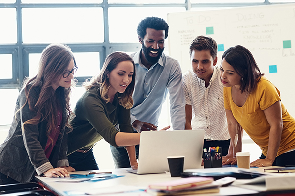 Group of office workers gathering around a computer