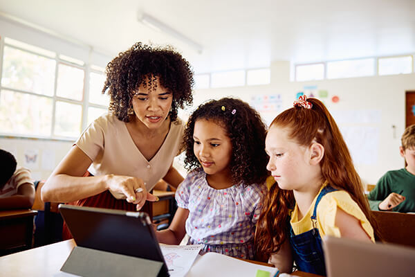 Teacher showing kids in classroom something on a computer