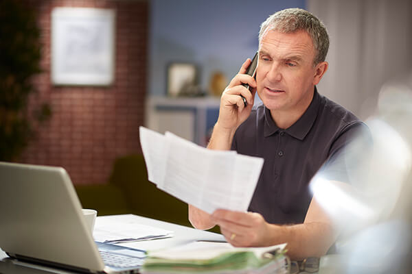 Man on phone looking at paperwork