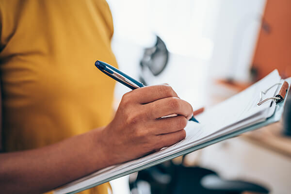 Woman writing on paper on a clipboard