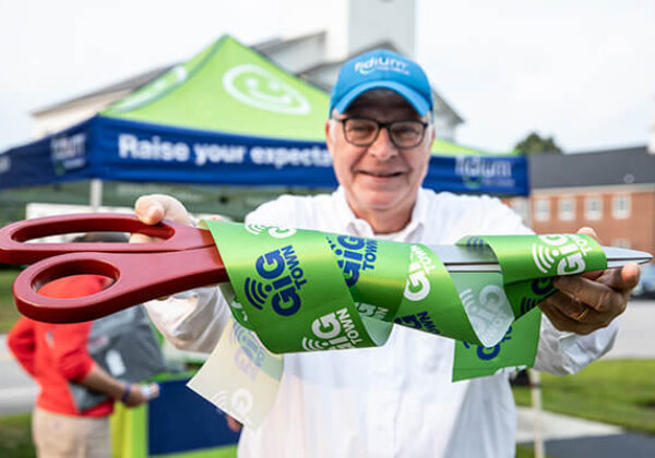 Man holding up scissors for ribbon cutting