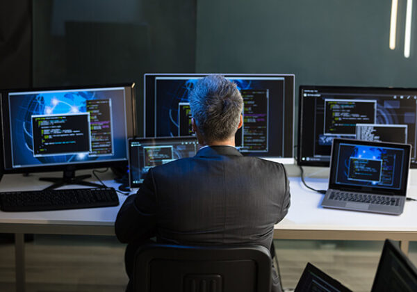 Man sitting at a desk monitoring many computers