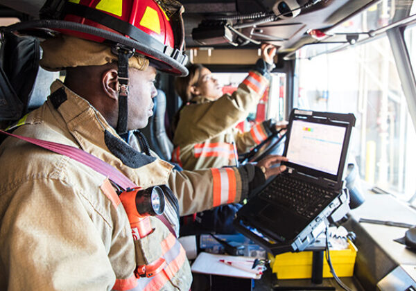 Two people in a fire truck looking at a computer screen