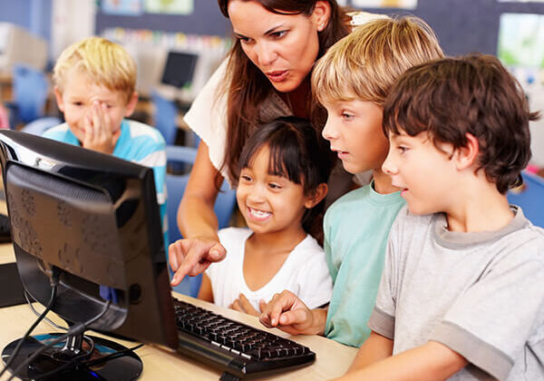 Teacher working with kids looking at a computer