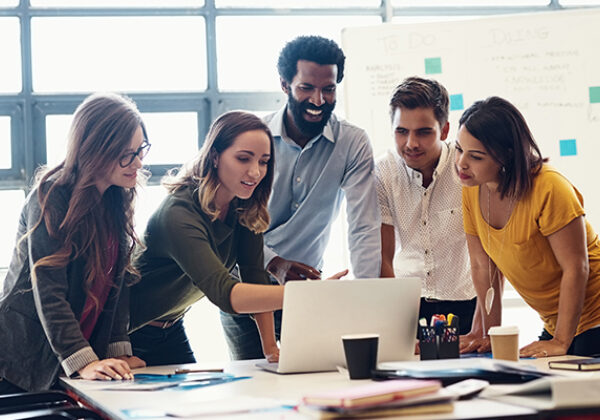 Group of office workers gathering around a computer