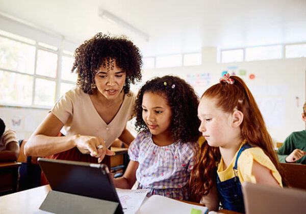 Teacher showing kids in classroom something on a computer