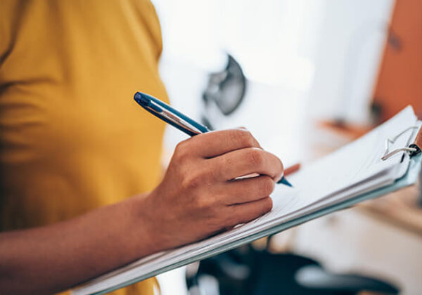 Woman writing on paper on a clipboard