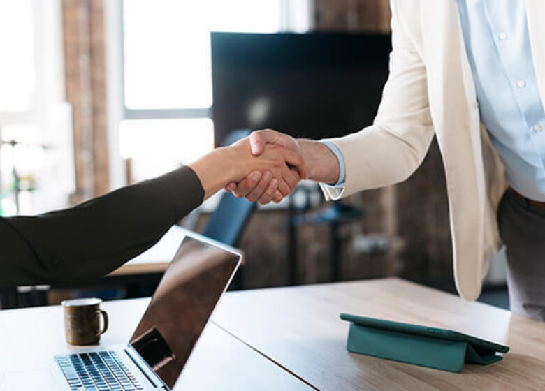 Two people shaking hands over a table