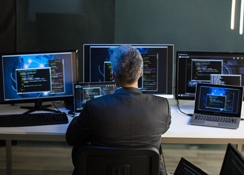 Man sitting at a desk monitoring many computers