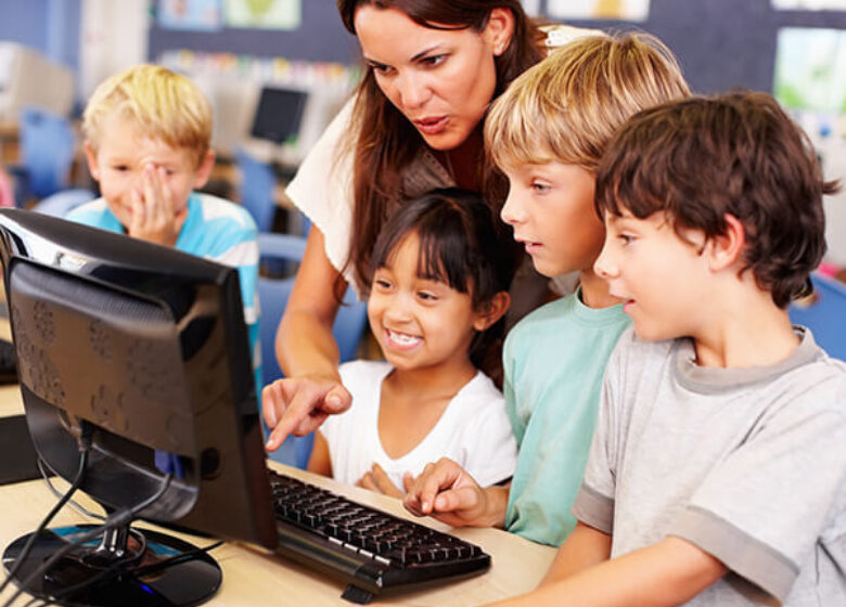 Teacher working with kids looking at a computer