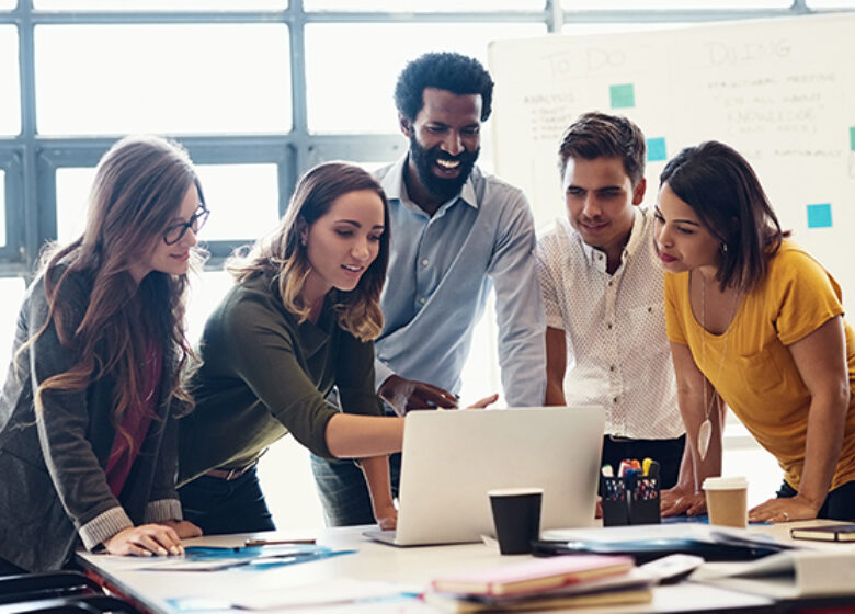 Group of office workers gathering around a computer