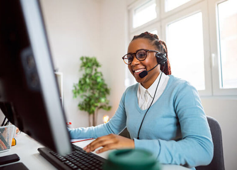Business U Caa S Sub Hero 600x400 Woman at desk with headset on talking on phone while working at computer