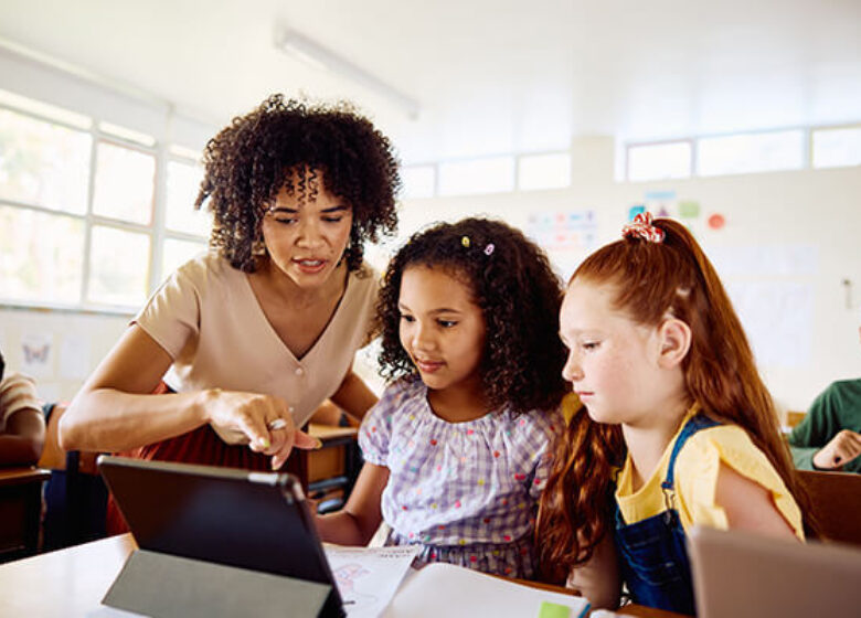 Teacher showing kids in classroom something on a computer