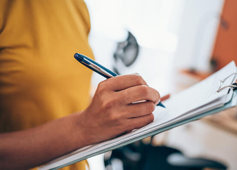 Woman writing on paper on a clipboard